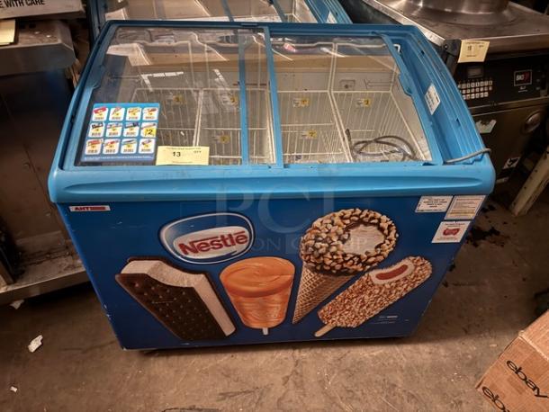 AHT RIO S 100 ice cream freezer merchandiser with sliding glass top, blue exterior, Nestlé branding, and illustrated ice cream graphics.