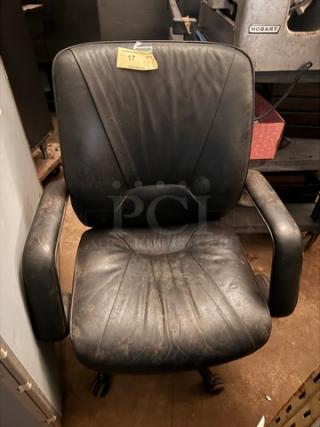 Black office chair with worn leather upholstery, cushioned armrests, and a swivel base. Visible wear indicates use. Tagged with number 17.