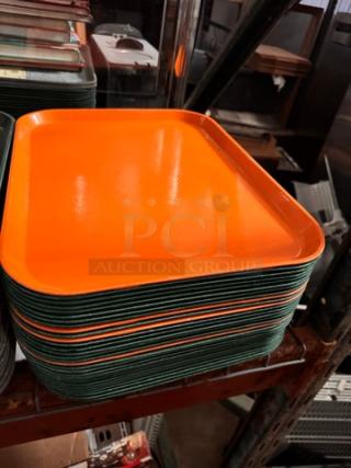 Lot of 32 orange rectangular plastic food trays, stacked on a shelf. Excellent condition, designed for durability.