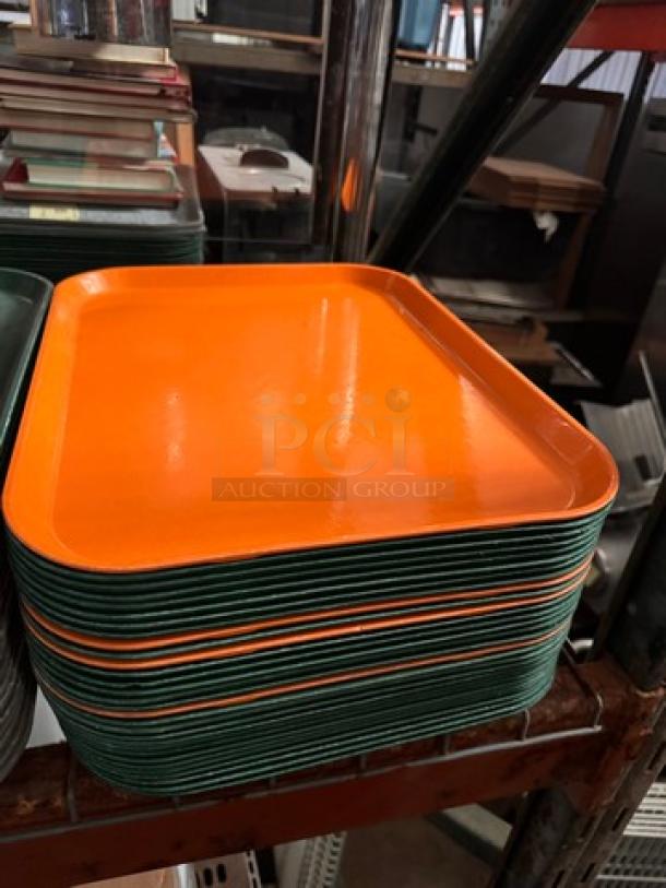 Lot of 32 orange and green plastic food trays, stacked on a shelf. Good condition, uniform design.