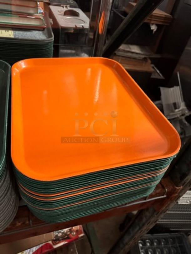 Lot of 32 plastic food trays, orange and green, stacked, good condition, rectangular. Suitable for cafeteria or restaurant use.