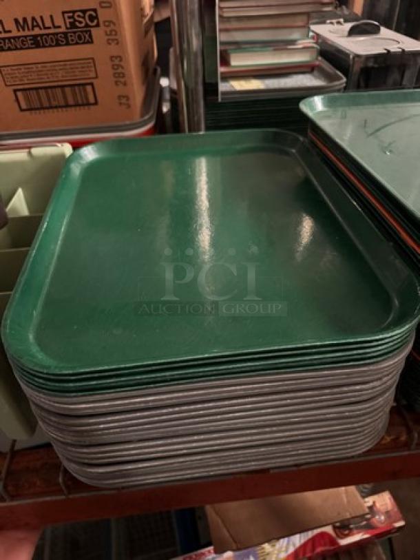Lot of 22 green plastic food trays, stacked, used condition, ideal for cafeteria or restaurant use.