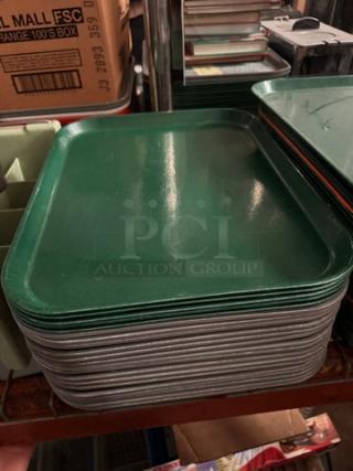 Lot of 22 green plastic food trays, stacked, used condition, ideal for cafeteria or restaurant use.