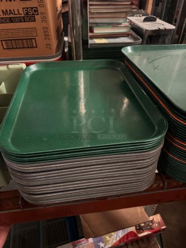 Lot of 22 green and gray plastic food trays in used condition, stacked on a shelf.