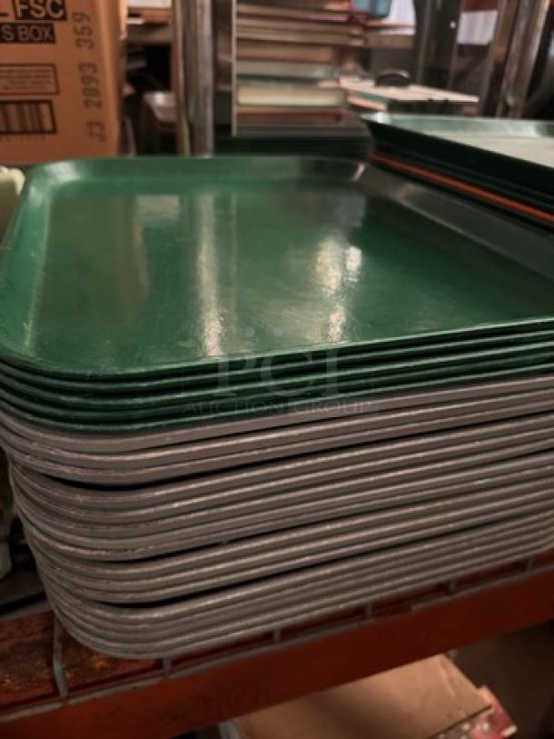 Lot of 22 green plastic food trays, stacked. Gently used, durable, ideal for cafeterias. No visible markings.
