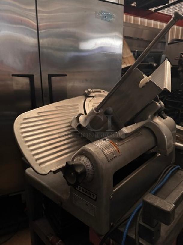 Hobart 1612E Meat Slicer, 115V, used condition, visible wear. Features adjustable thickness control and stainless steel blade.