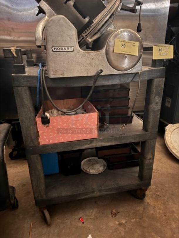 Heavy-duty utility cart with three shelves, metal frame, on casters. Contents shown not included. Sturdy design for versatile use.