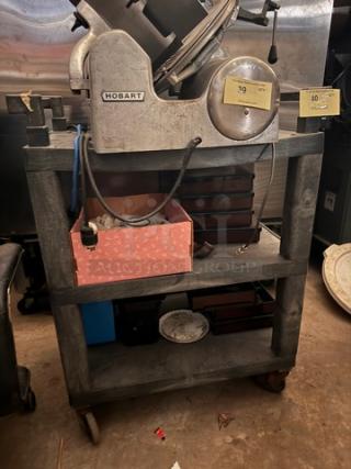 Heavy-duty utility cart with three shelves, metal frame, on casters. Contents shown not included. Sturdy design for versatile use.