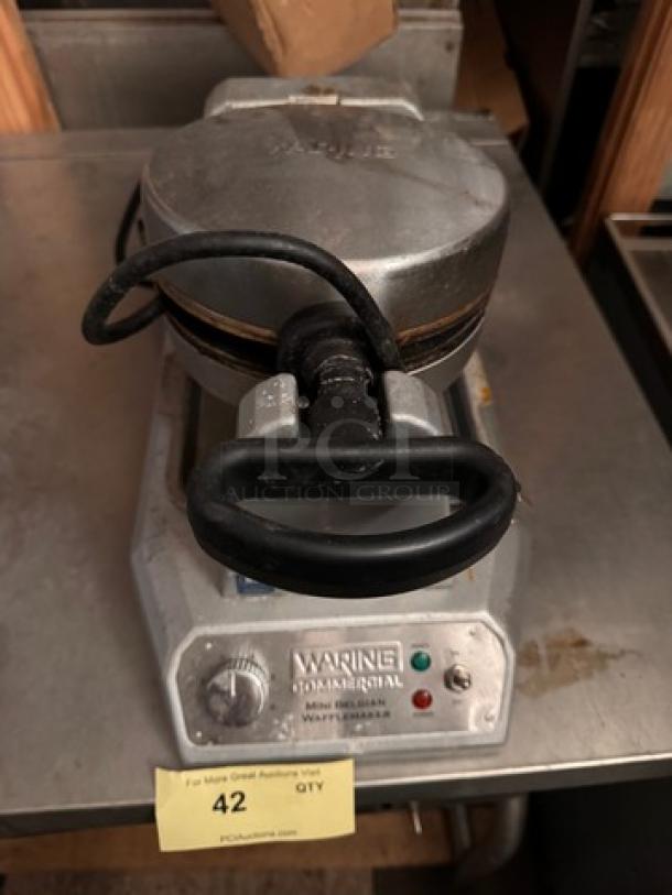 WARING Mini Belgian Waffle Maker, stainless steel, commercial-grade, visible wear, model identifier on label, functional knobs.