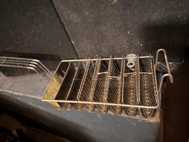Stainless steel taco fryer basket with six slots, used condition. Ideal for frying taco shells, showing some wear on metal finish.