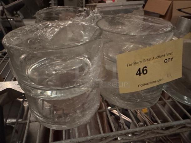 Lot of 9 clear glass bowls wrapped in plastic. Visible auction tag showing quantity and label from PCI Auctions.