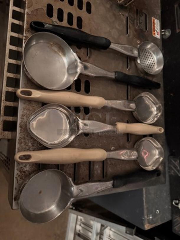 Set of metal food portion serving spoons with plastic handles in various sizes, in used condition.