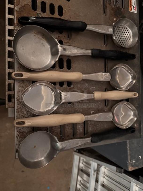Set of seven metal food portion/serving spoons with plastic handles, various sizes and shapes, in good condition.