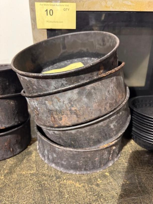 Rustic metal baking pan stack, model BIDX4, showing signs of wear and patina. Auction lot labeled "10 QTY."