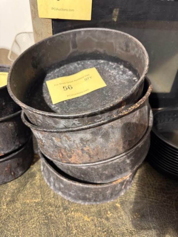 Stack of vintage round baking pans with rusted surfaces, labeled "BIDX4" and "56 QTY". May need restoration.