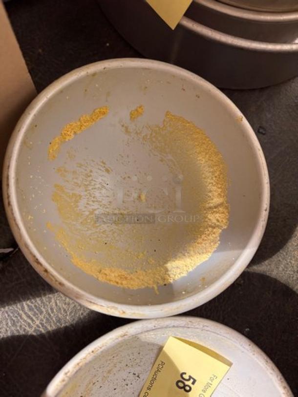 Round metal baking pan BIDX2 with remnants of flour inside, showing signs of use. Auction tag labeled "38" visible.