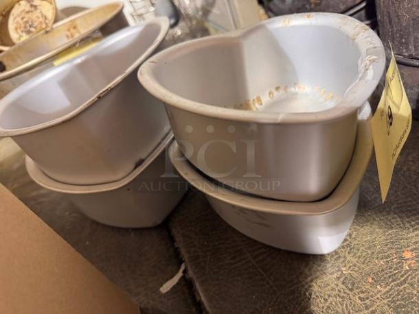 Four silver heart-shaped baking pans, used condition, some discoloration and stains visible. Tag reads "19 Auction Lot."
