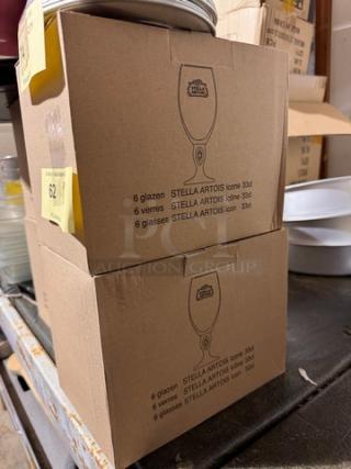 Two boxes of STELLA Artois glasses, each containing six 33cl glasses, labeled in multiple languages.