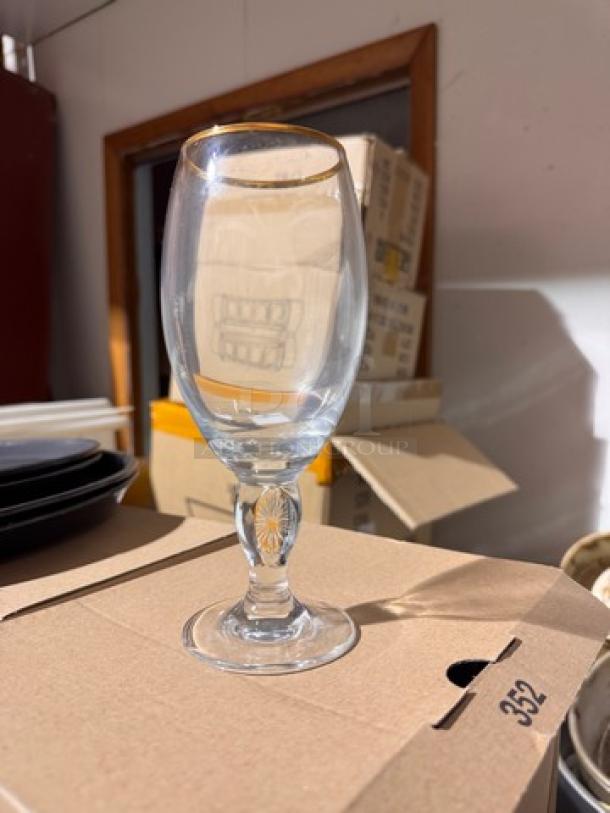 Clear glass with golden rim, part of STELLA 12 glasses set, displayed on a cardboard box.