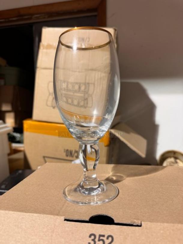 Clear stemmed glass with a gold rim, part of "STELLA 12 Glasses" set. Appears in good condition, no visible markings.