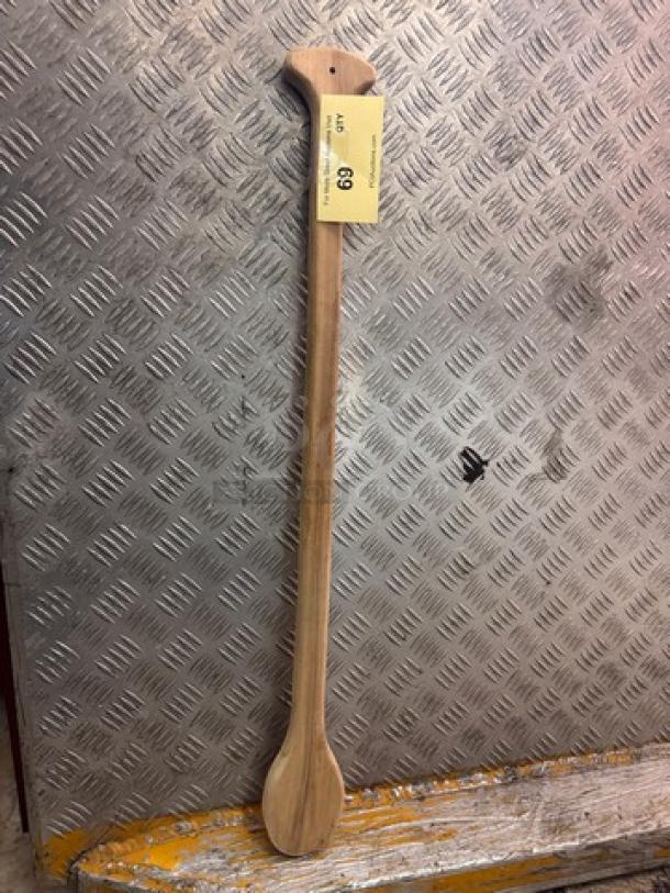 Wooden cooking paddle, long handle, natural wood finish, attached tag indicating item number 68, textured background.