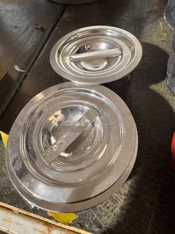 Two stainless steel containers with lids labeled BIDX2, reflecting light; appear in good condition.