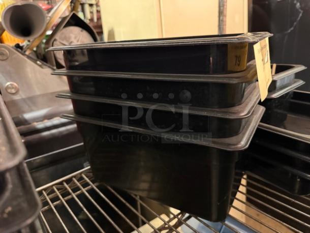 Stack of black 1/3X6IN food pans, BIDX4 model, in good condition. Auction tag visible.