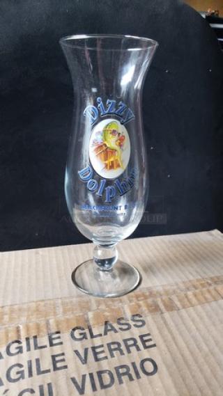 23.5 oz hurricane glass with "Dizzy Dolphin" logo, clear glass, part of a dozen set, new condition, on "fragile glass" box.