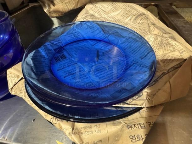 Lot of blue glass cereal bowls and plates on newspaper, in good condition.