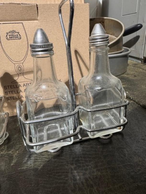 3-piece oil and vinegar cruet set with rack, features two clear glass bottles, metal caps, and a sturdy metal rack. Stella Artois branding visible on box.