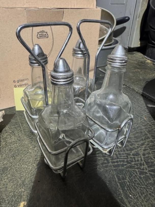 3-piece oil and vinegar cruet set with metal rack, featuring clear glass bottles and metal pour spouts. Good condition.