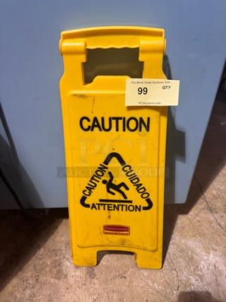 Yellow folding CAUTION sign with multilingual warning text and slip hazard icon. Brand mark at bottom. Good condition.