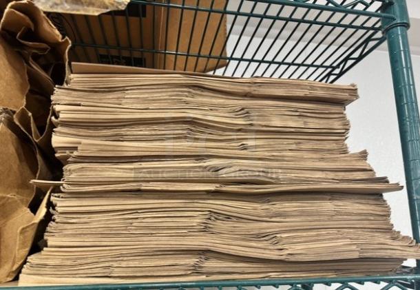 Stack of 1/6 size paper bags on a metal shelf. Bags are unfolded and stacked neatly, indicating unused condition.