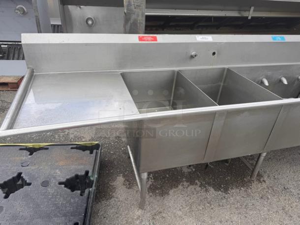 140" 4 bay commercial stainless steel sink with back splash and side drainboard. Features four compartments, faucet fixtures.