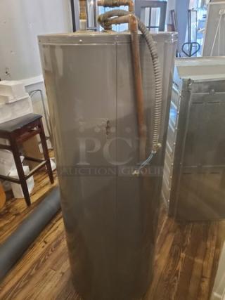 Rheem Performance 50 Gal. 4500-Watt Electric Water Heater in good condition, metal exterior, visible piping.