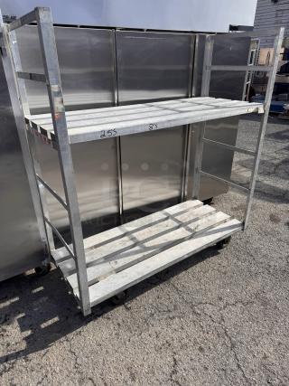 Aluminum storage rack on casters, two shelves, used condition, markings with numbers on shelves, mobile and sturdy design.