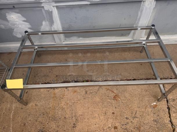 Stainless steel dunnage rack with a sturdy metal frame, in good condition, suitable for storage and organization.