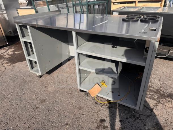 Industrial metal stand with open shelves, work surface, and electrical access. Used condition with visible wear. Great for commercial use.