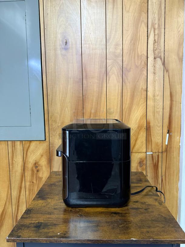 Instant Pot Vortex Plus 10 Quart Air Fryer Oven, black, side view, on wooden surface, power cord visible.