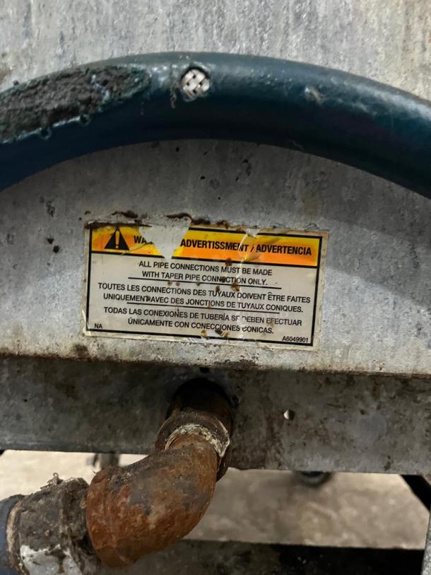 Alt Text: Pitco SG14-S gas fryer with 40-50 lb. capacity and 110,000 BTU, features a warning label on pipe connections.