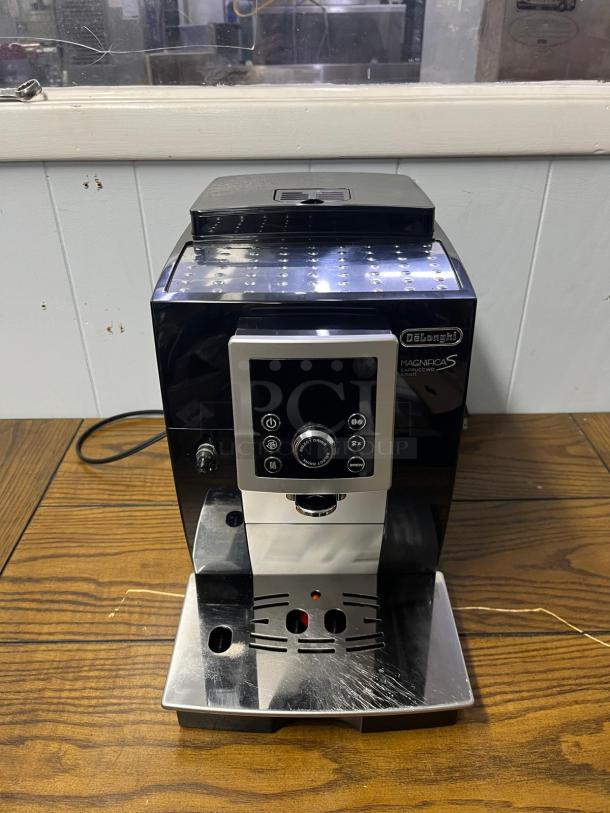 De'Longhi Magnifica S espresso machine with built-in grinder, black-silver, used condition, visible controls and markings.