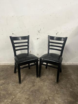 Cafe dining chairs with black frames and padded vinyl seats, showing some wear on legs. Suitable for dining setting.