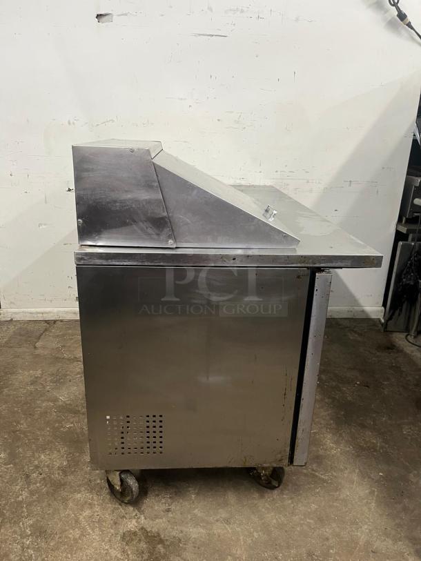 TRUE TSSU-60-12M-B-HC refrigerated sandwich prep table, stainless steel, 60 3/8", two doors, side view, on wheels.