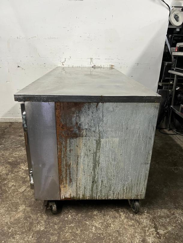 Universal Cooler 3 Door Worktop, stainless steel, visible rust and wear, on wheels, industrial use, as-is condition.