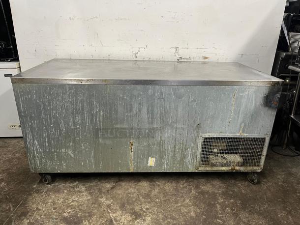 Universal Cooler 3-door worktop with visible wear and rust, stainless steel surface, vented panel, and casters.