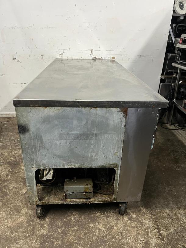 UNIVERSAL COOLER 3 Door Worktop in used condition, visible wear on surface and edges, mounted on wheels for mobility.