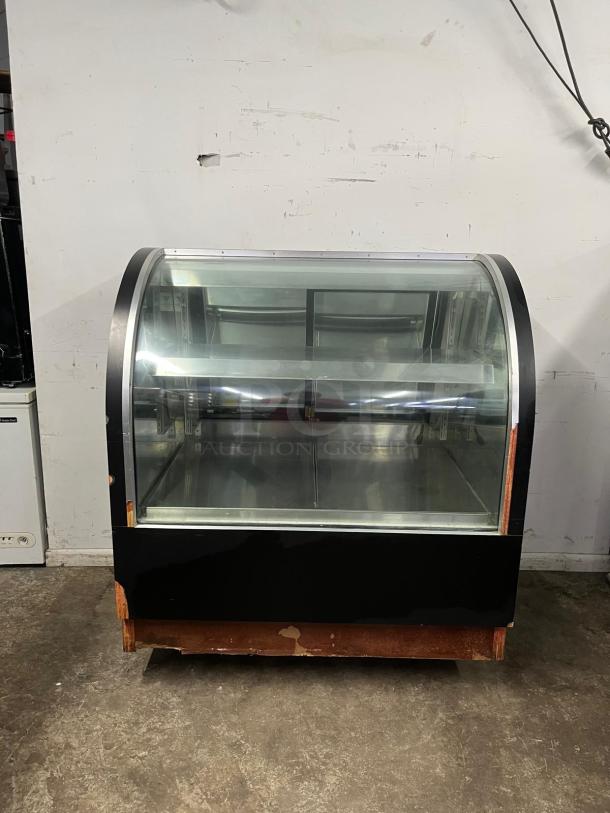 36" curved refrigerated display case with glass front, showcasing interior shelving. Black exterior, used condition.