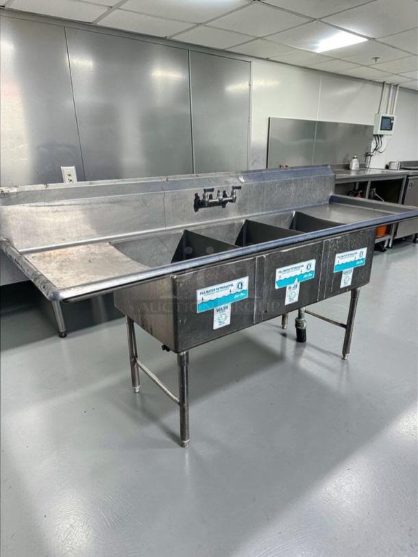 Immaculate 3-compartment stainless steel sink with dual drainboards, NSF-certified, by Commercial Stainless Steel Fabrication.