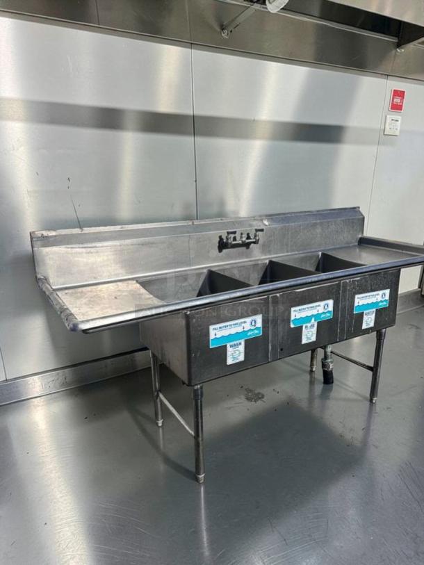 Immaculate Commercial Stainless Steel 3-compartment sink with dual drainboards, NSF certified, ready for installation.
