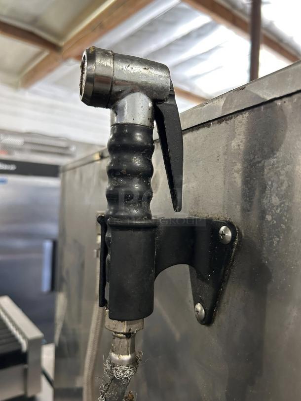 Close-up of a commercial oven sprayer handle attached to BKI ETE102R combi oven. Metal and rubber handle in used condition.